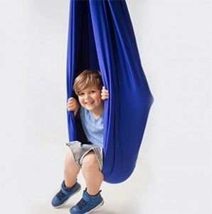Niño sonriente disfrutando en un columpio sensorial azul para estimulación vestibular y desarrollo sensorial